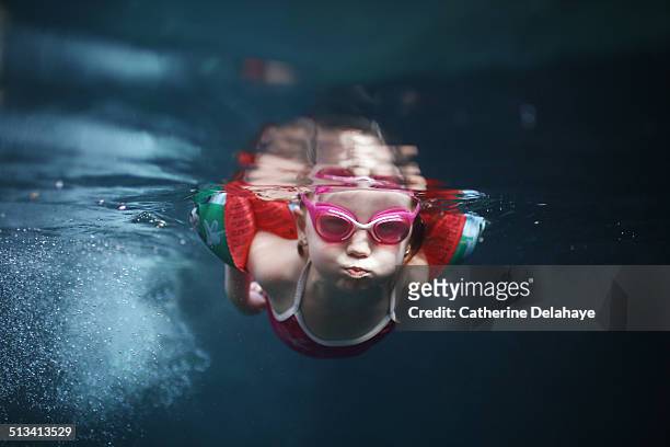 a 4 years old girl swimming under water - brazaletes acuáticos fotografías e imágenes de stock
