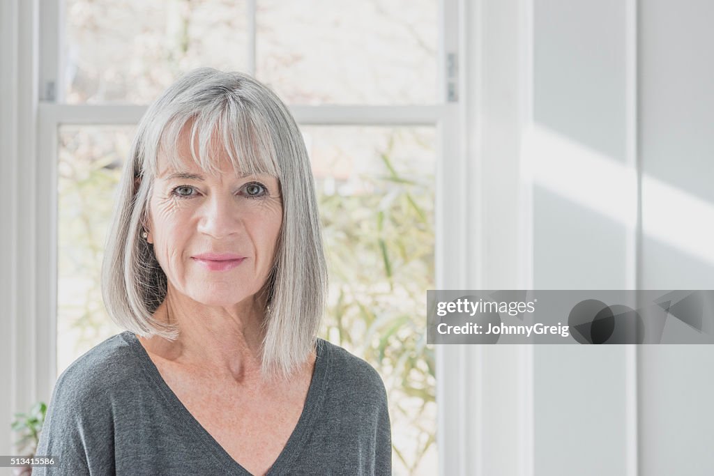 Portrait of senior woman by window with grey bob