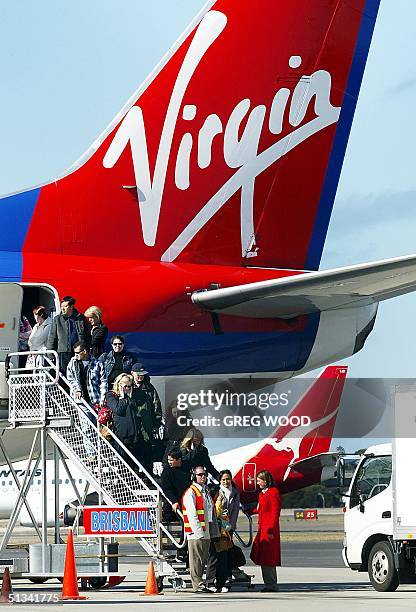 Passengers disembark from a Virgin Blue plane after arriving at Sydney Airport, 31 July 2002, as a Qantas jet taxis past. Chris Corrigan, head of the...