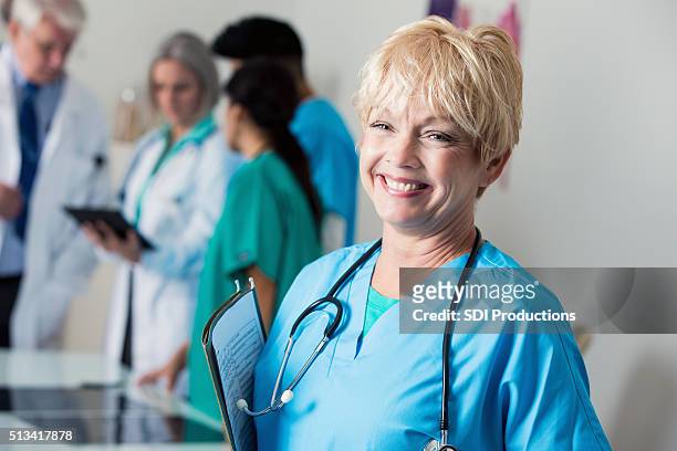 senior doctor or nurse smiles in staff meeting - emergency department stock pictures, royalty-free photos & images