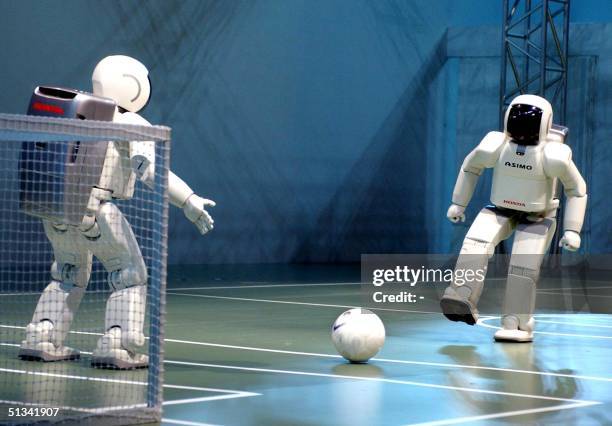 Japan's automaker Honda's humanoid robots ASIMOs play soccer during a demonstration at the Robocup 2002, robot's world cup event in Fukuoka, western...