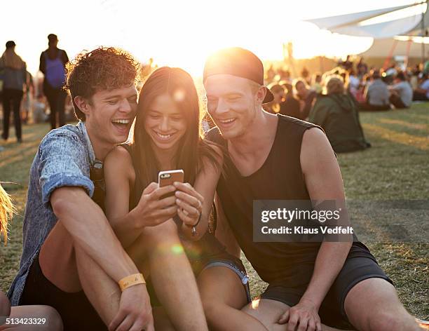 friends laughing, while looking at smartphone - music festival phone stock pictures, royalty-free photos & images