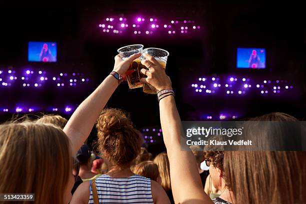 two women toasting in beer at concert - blonde cheering stock-fotos und bilder