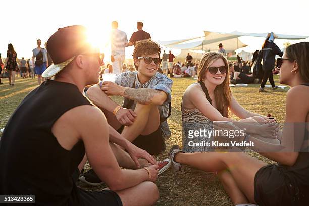 friends sitting on grass, drinking beer - drinking beer festival stockfoto's en -beelden