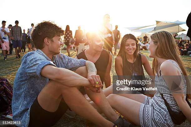 friends sitting on grass at sunset - music festival grass stock pictures, royalty-free photos & images