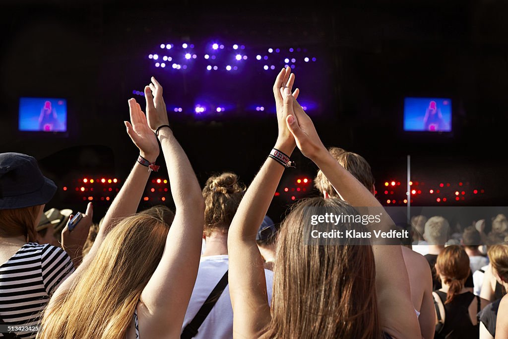 Women clapping hands at big concert