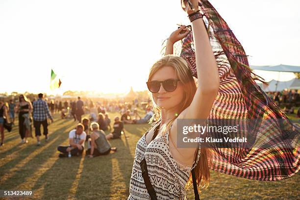 cute young woman holding up scarf at sunset - festivalganger stockfoto's en -beelden