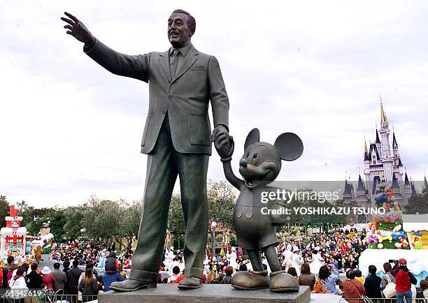 Walt Disney and Mickey Mouse statues stand at the Tokyo Disneyland in Urayasu city, suburban Tokyo while visitors enjoy Disney characters' parade 13...