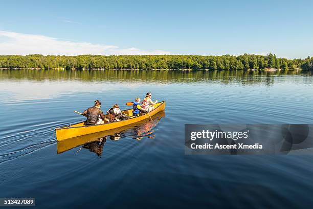 women and children paddle canoe into tranquil lake - combine day 6 stock-fotos und bilder