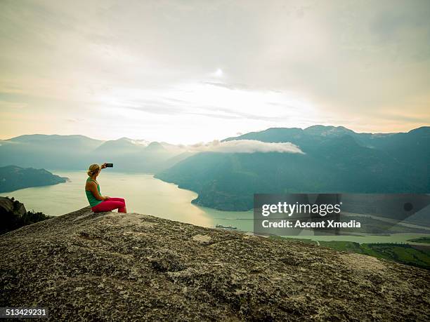 woman takes smart phone pic on mtn summit - canadian wilderness stock pictures, royalty-free photos & images