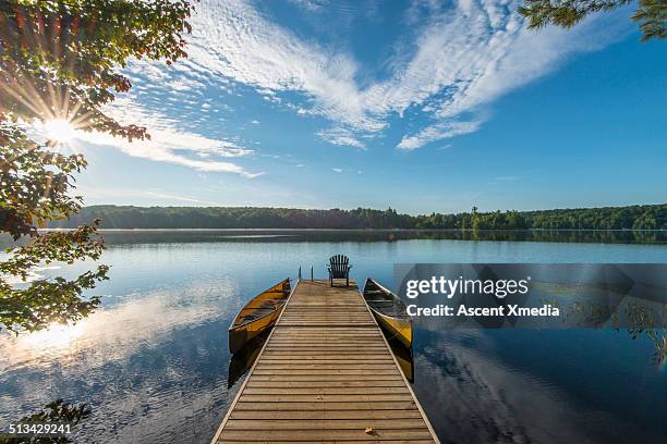 wooden pier reaches into tranquil lake, sunrise - bootssteg stock-fotos und bilder