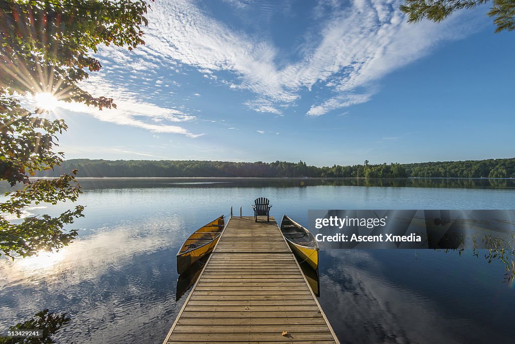 Wooden pier reaches into tranquil lake, sunrise