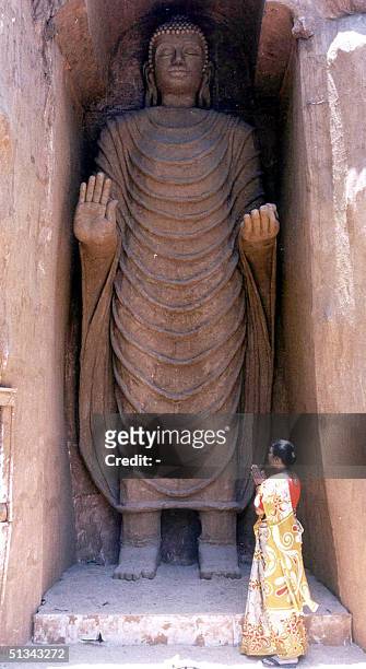 Buddhist devotee prays 08 May 2001 in front of a 30 feet tall replica of the Bamiyan Buddha erected on the occasion of Buddha's birthday 07 May. The...