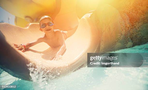 little boy having fun sliding in water park - water slide stockfoto's en -beelden