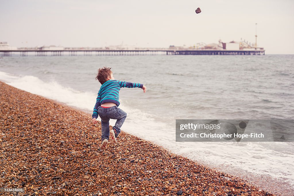 Young boy throwing a stone on a beach