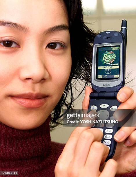 Japan's electronics giant NEC employee, Hanayo Awano, displays the company's latest mobile phone N503i which has installed JAVA Script computer...