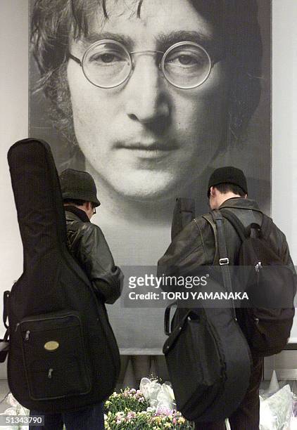 Japanese visitors, carrying guitars, pray in front of a big portrait of former British musician John Lennon at the John Lennon Museum in Omiya, in...