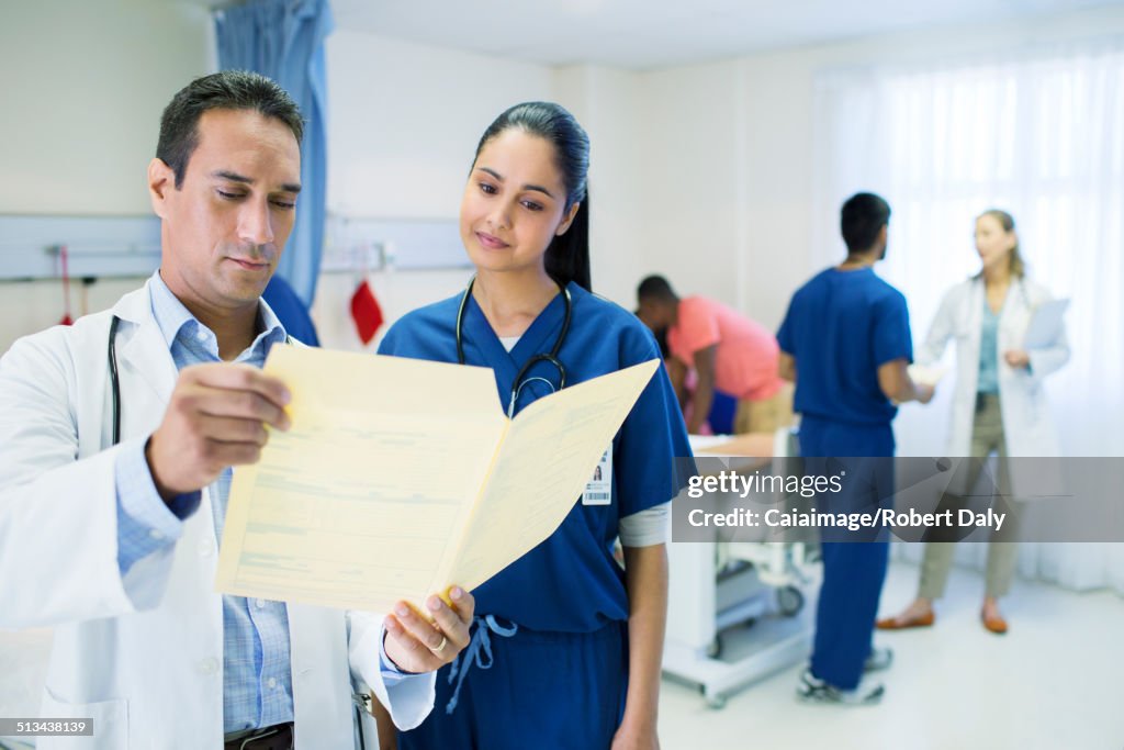 Doctor and nurse reading medical chart in hospital room