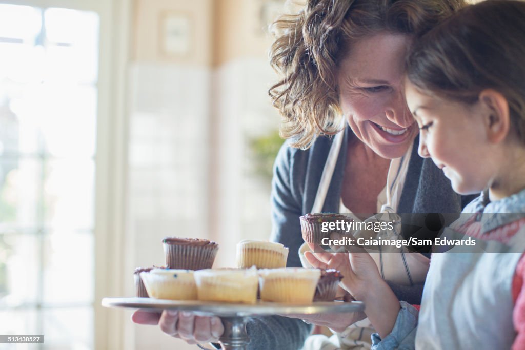 Grandmother offering granddaughter cupcakes
