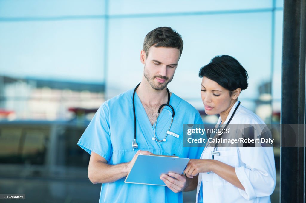 Doctor and nurse reading medical chart outdoors