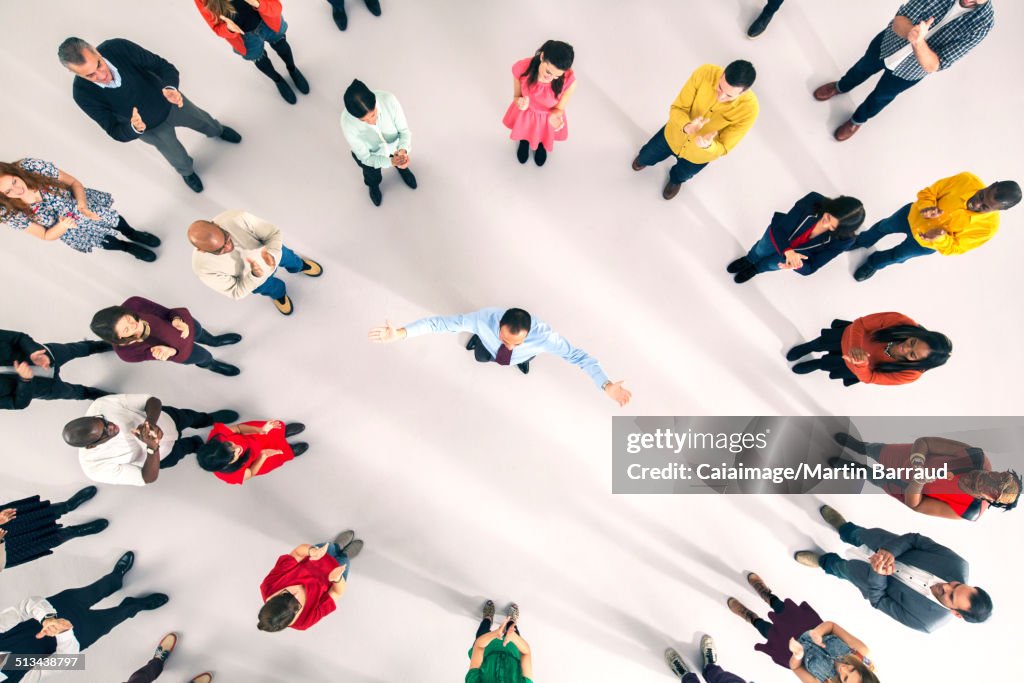 Crowd around businessman with arms outstretched