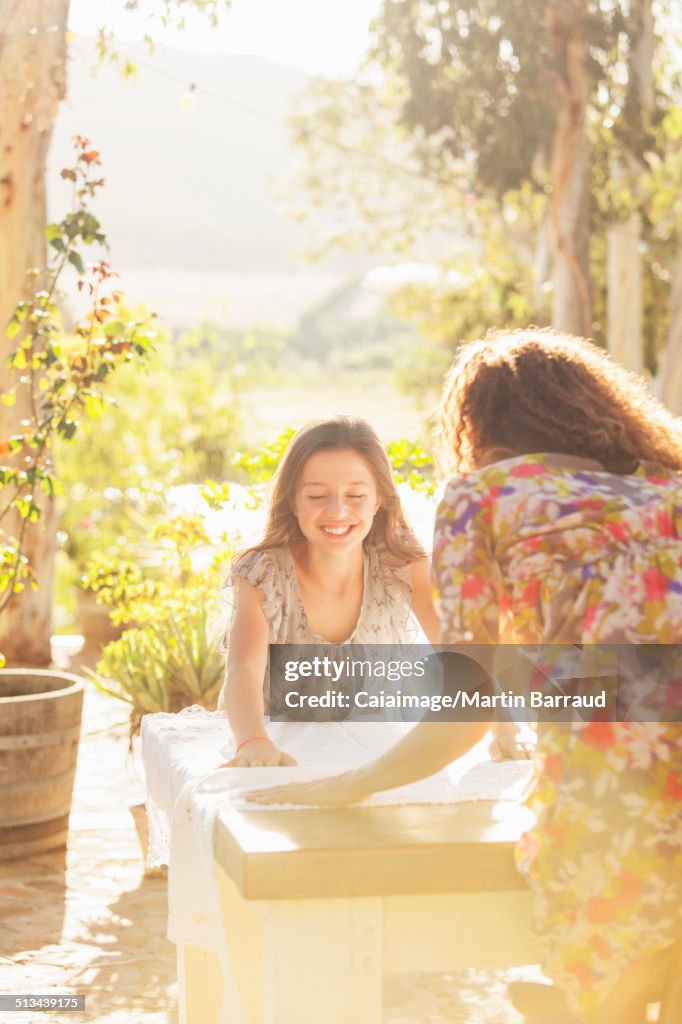 Mother and daughter laying table cloth on table