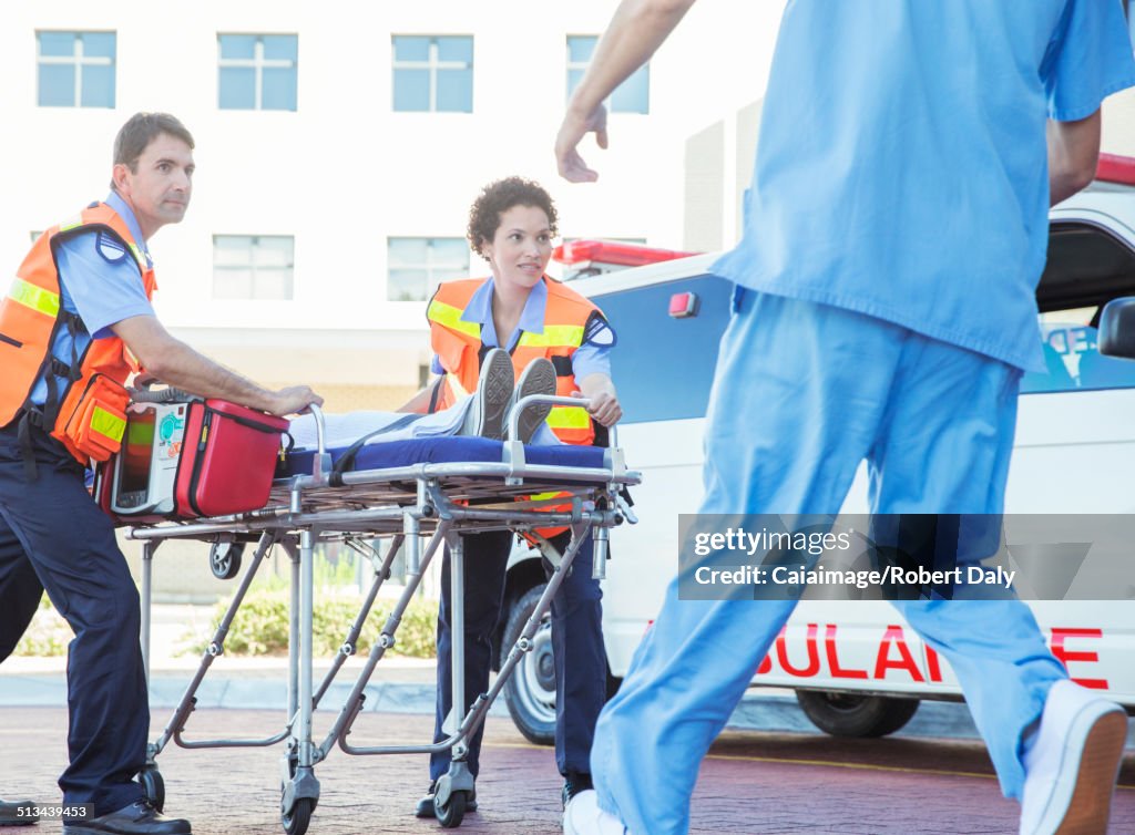 Paramedics wheeling patient in hospital parking lot