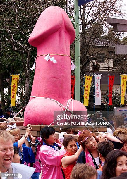 People carry a large phallus-like portable shrine on their shoulders during the annual Kanamara festival at a shrine in Kawasaki, in suburban Tokyo...