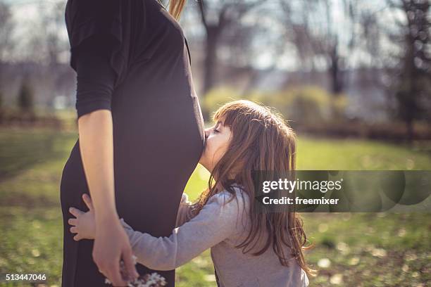 niedlich mädchen küssen ihre mutter schwangeren bauch - belly kissing stock-fotos und bilder