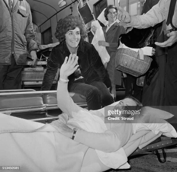 British racing driver and team owner, Graham Hill is carrried from an airplane accompanied by his wife, Bette, on arrival from America to London...