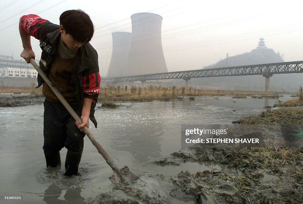 A young migrant worker shovels heavily polluted mu