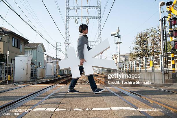 a man carrying yen shape object and crossing - japanese currency stock pictures, royalty-free photos & images