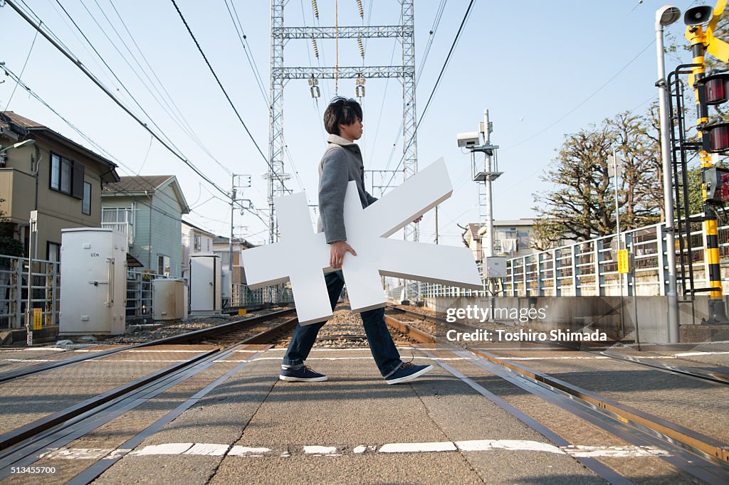 A man carrying Yen shape object and crossing