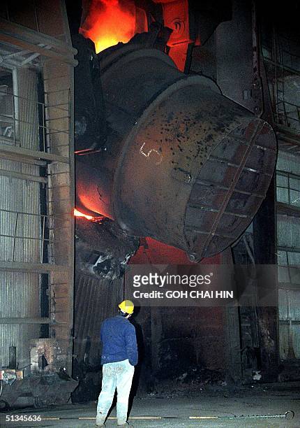 Steel mill worker watches a cauldron fire up at a steel mill in Beijing 07 June 1999. China became the world's biggest steel producer in 1996 and...
