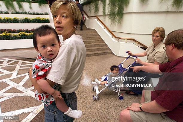 American Denise Reed of St Louis holds her newly adopted daughter Zoey in the lobby of a hotel situated next to the American Consulate in Guangzhou...