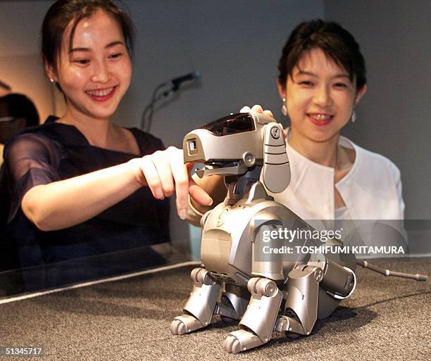 Ladies from Sony Corporation's PR section play with the company's new entertainment robot 'Aibo' during its press preview 11 May 1999 in Tokyo. Sony...