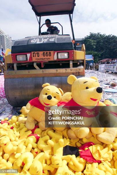 Pile of counterfeit Winnie-the-Pooh dolls await their fate in front of a steamroller crushing the counterfeit goods 26 November during Thailand's...
