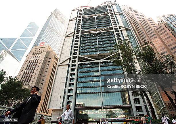 Man talks on his portable phone 16 November as he passes in front of the Hong Kong and Shanghai Bank Building, the Hong Kong headquarters of British...