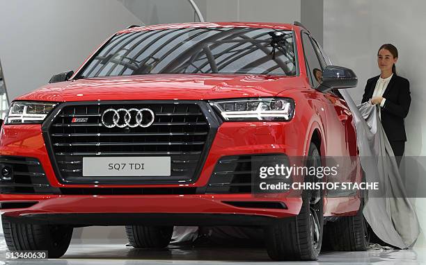 Hostesses unveil a model of Audi's new Q7 SUV car during a presentation at the company's annual press conference in Ingolstadt, southern Germany, on...