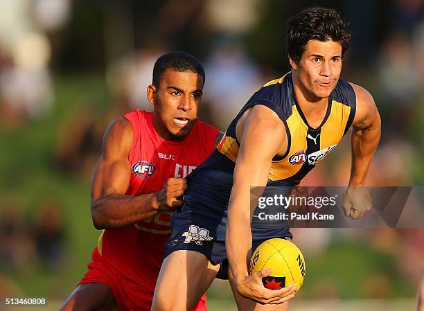 Liam Duggan of the Eagles looks to handball while being tackled by Touk Miller of the Suns during the 2016 AFL NAB Challenge match between the West...