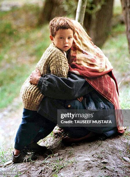 Frightened child holds onto her mother 20 September as they shift to the safer place following shelling between India an Pakistan in Kargil, some...