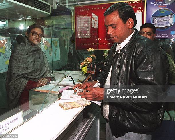 Non Resident Indian counts his rupee notes after changing US dollars at a currency exchange outlet in downtown New Delhi 14 January, as the rupee's...