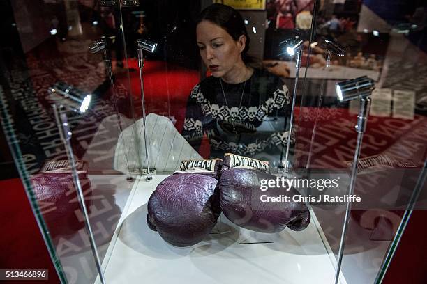 Curator Shannon Pratt polishes a case containing Muhammad Ali's gloves used to fight Joe Frazier from the 'Fight of the Century' at Madison Square...