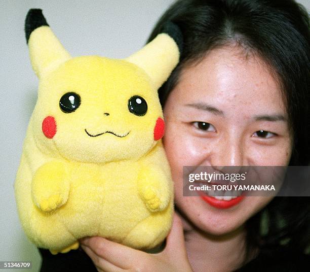 Young woman holds a stuffed toy, the mouse monster Pikachu, hero of a video game and animated television programm "the Pocket Monster", in Tokyo 17...