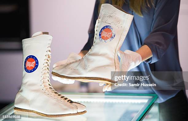 An exhibition assistant holds a pair of signed boots, worn by Muhammad Ali during his 1975 championship fight against Jimmy Young, during a preview...