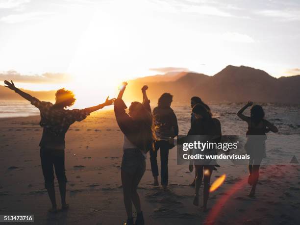 jeunes amis danser sur la plage au coucher de soleil - été fêtes photos et images de collection