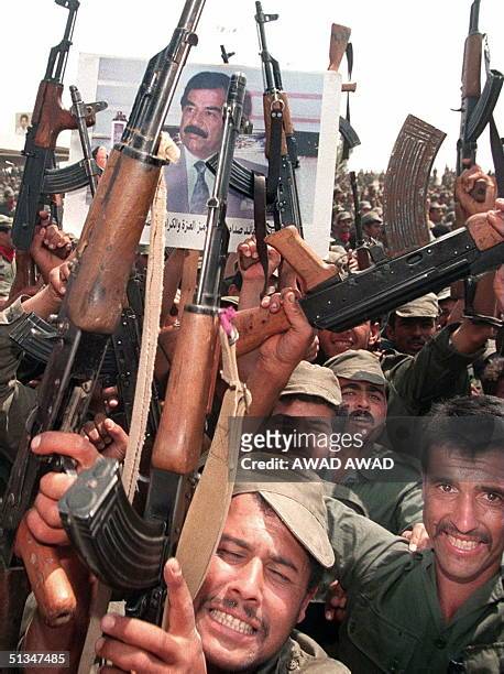 Iraqi soldiers hold up their arms during celebrations to mark the 61st birthday of Iraqi President Saddam Hussein 28 April 1988, in his home town of...