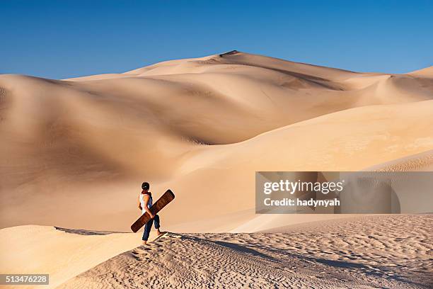 young woman sandboarding in the sahara desert, africa - sand boarding stock pictures, royalty-free photos & images