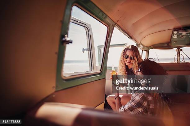 junge hipster-paar lächelnd und rösten bier in retro-van - us girls on the beach stock-fotos und bilder