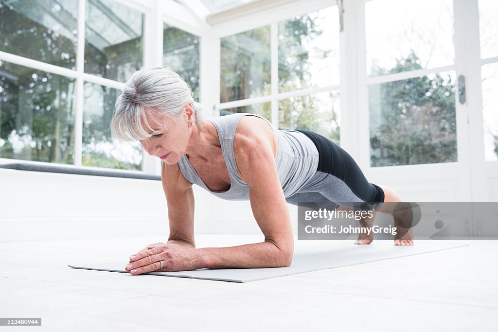 Senior woman in plank position in conservatory